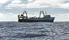 Commercial fishing trawler is fishing for marine fish and seafood in oceanic waters. Large fishing vessel lifts trawl tackle in the southern waters of the Atlantic.
