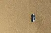 Aerial view of a single fishing boat on the dry surface of a drought lake bed. Taken via drone. Burdur, Turkey.