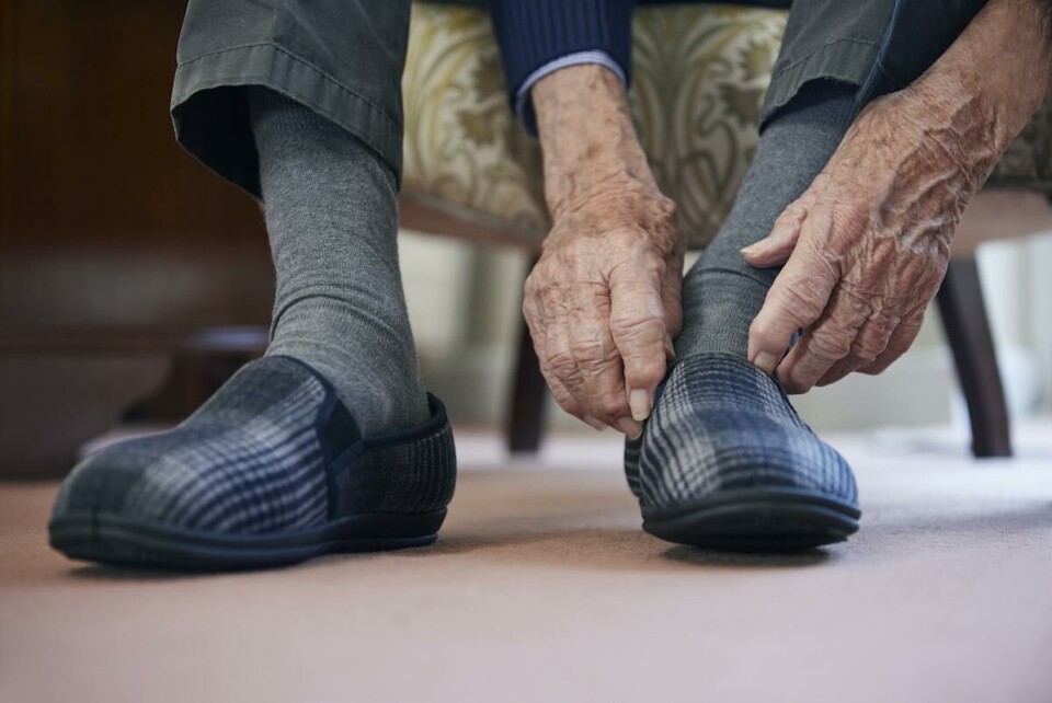 Alla som har fyllt 80 år och bor hemma borde få gratis trygghetslarm. Det är ett av kraven i listan. Close Up Of Senior Man Putting On Slippers To Keep Feet Warm In Cost Of Living Crisis