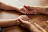 Cropped shot of a man and woman holding hands in comfort on a table