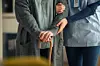 Close up hands of caregiver doctor helping old woman at private clinic. Close up of hands of nurse holding a senior patient with walking stick. Elder woman using walking cane at nursing home with nurse holding hand for support.